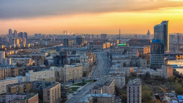 A breathtaking view of Moscow's urban landscape with the sun setting, highlighting the city's architecture.