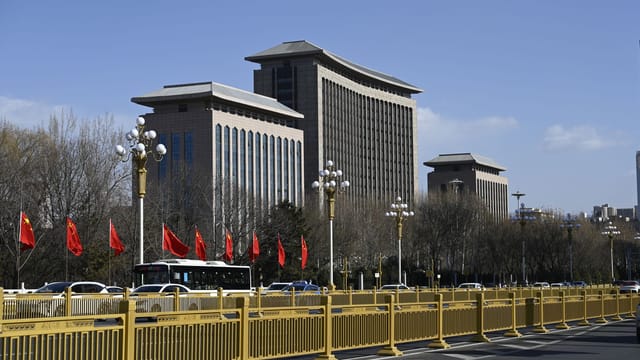 Street view of modern buildings with red flags in Beijing on a clear day.
