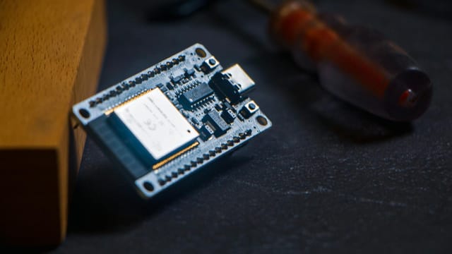 Microcontroller chip with screwdriver on dark surface, ideal for tech and innovation themes.
