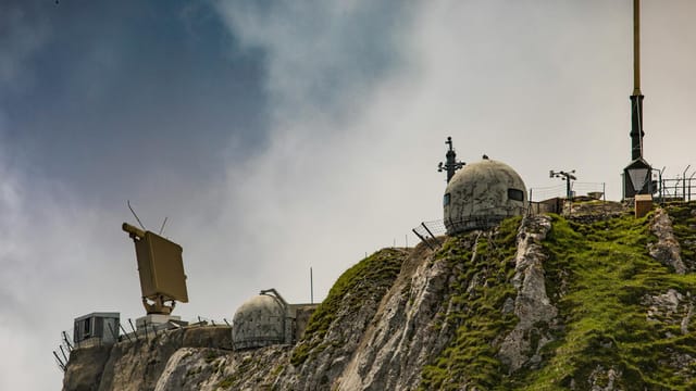 Swiss radar system perched on a rugged mountainside, showcasing technical and natural contrast.