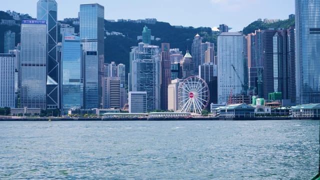 Stunning view of Hong Kong skyline with skyscrapers and observation wheel from Victoria Harbour.
