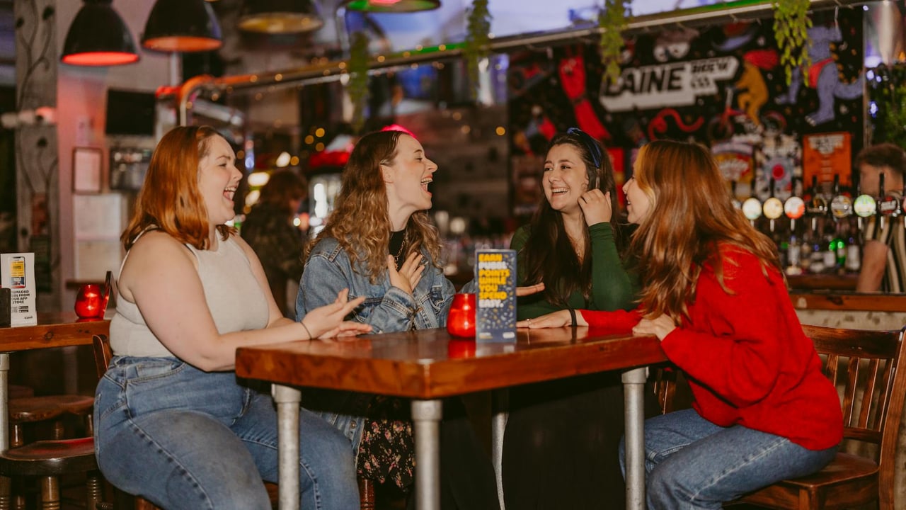 Four women enjoying conversation in a lively Islamabad cafe with colorful decor.