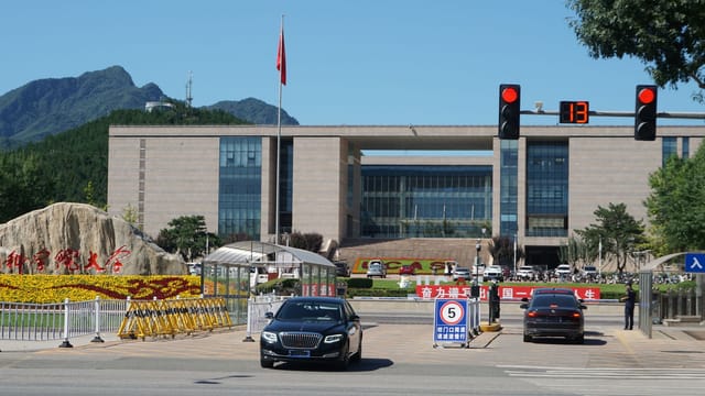 Main entrance of China Agricultural University with building and mountains in the background.