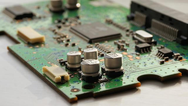 Detailed view of a green circuit board featuring capacitors and microchips.