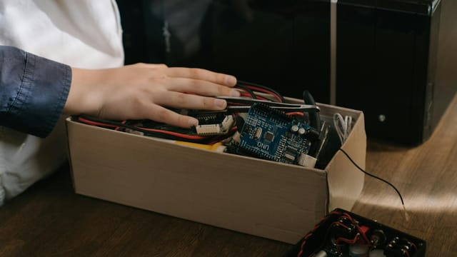 Close-up of hand interacting with Arduino microcontroller kit for electronic projects.