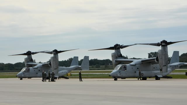 Two military aircraft parked at an airbase with personnel nearby, showcasing aviation technology.