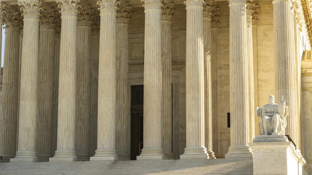 The Supreme Court of the United States with iconic marble columns and statue, captured in natural light.