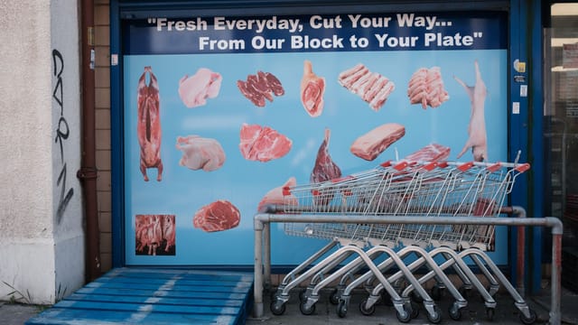 Butcher shopfront advertising meats with shopping trolleys in Swindon, UK.