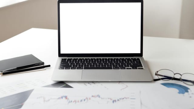 Open laptop with financial documents on a desk, ideal for business and technology themes.