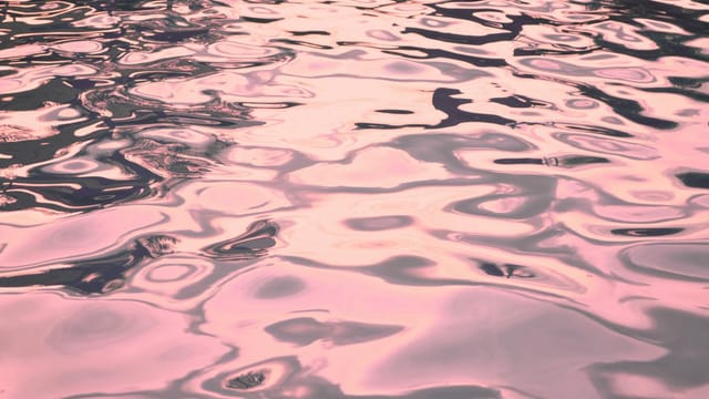 A beautiful abstract view of water ripples reflecting pink hues, creating a serene atmosphere.