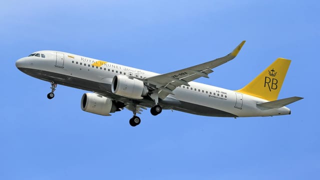 Royal Brunei Airlines aircraft soaring in clear blue sky, showcasing aviation excellence.