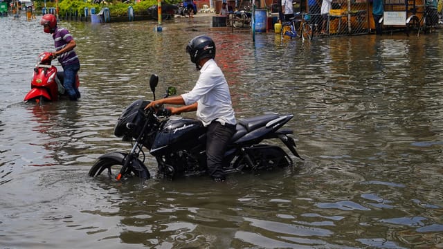 Motorcyclists navigate through a flooded street in Kolkata, India.