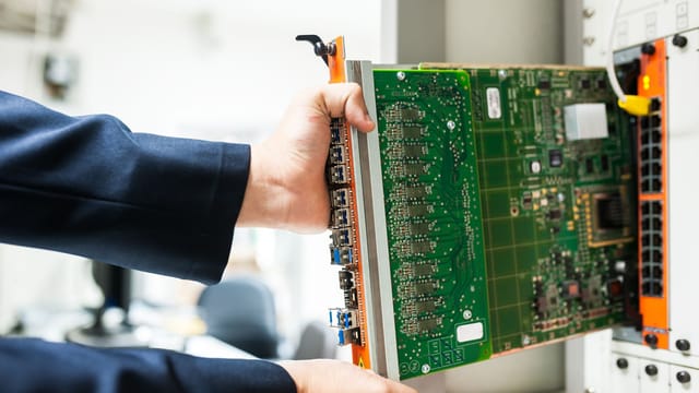 A technician inserts a circuit board into a server rack, illustrating technology and connectivity.