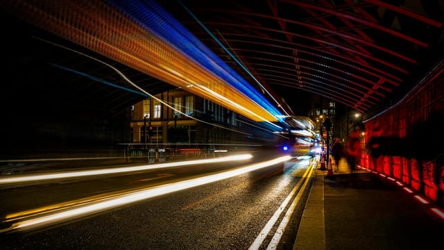 Vibrant light trails in an urban night tunnel create a dynamic and colorful scene.