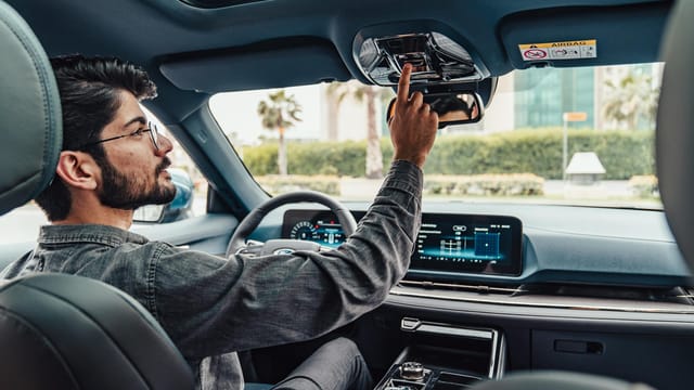 A man adjusts the interior features of a modern car while driving in Erbil, Iraq.