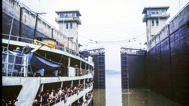 A crowded ferry navigates through a massive lock with towering walls, showcasing maritime infrastructure.