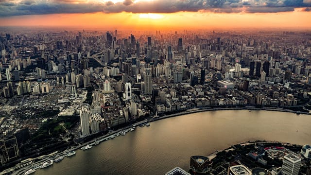 Stunning drone view of Shanghai's vibrant skyline and river at sunset.