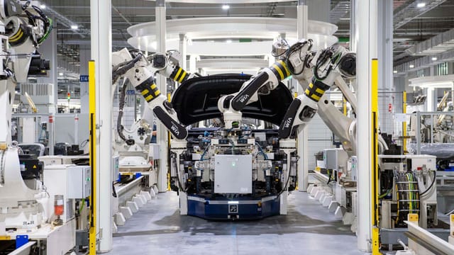 Illustrative image: High-tech robots assembling a car in a modern factory setting, showcasing automation.