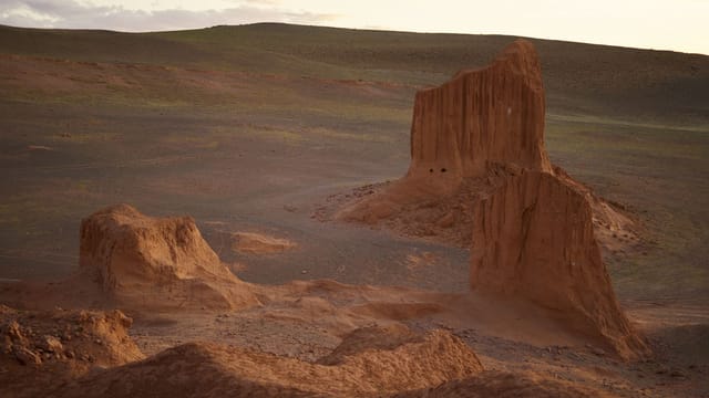 Majestic aerial view of red cliffs in empty desert valley under bright sky in coming evening