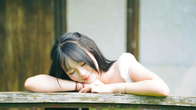 A serene image of a woman resting her head on a wooden railing, creating a calm and peaceful atmosphere.