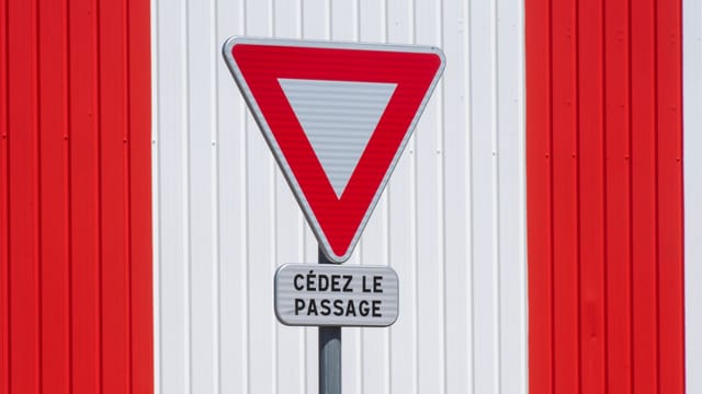 Yield sign with 'Cédez le passage' text on red and white striped background.