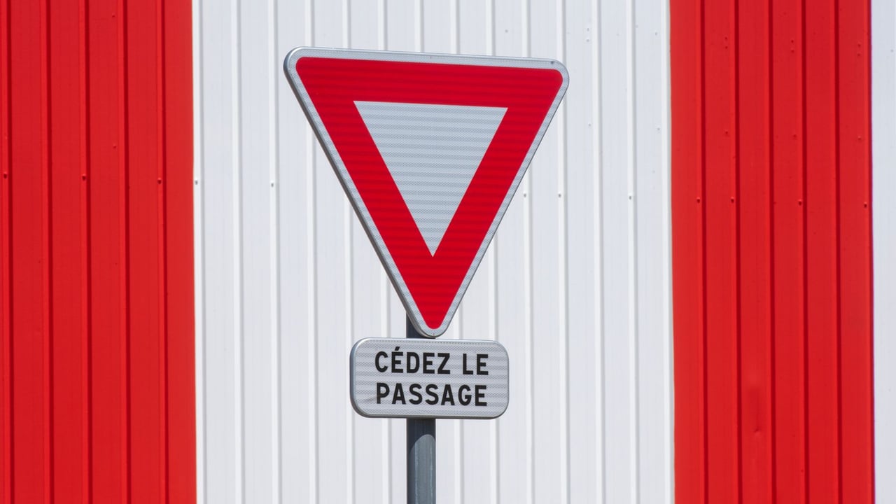 Yield sign with 'Cédez le passage' text on red and white striped background.