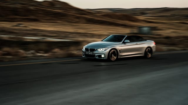 Illustrative image: A sleek silver convertible car captures motion on a highway, showcasing luxury and speed.