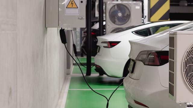 Electric vehicles charging at an indoor station in a modern underground garage.