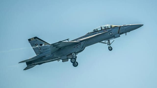 The Boeing F/A-18 Super Hornet depicted in a clear blue sky, showcasing military aviation prowess.