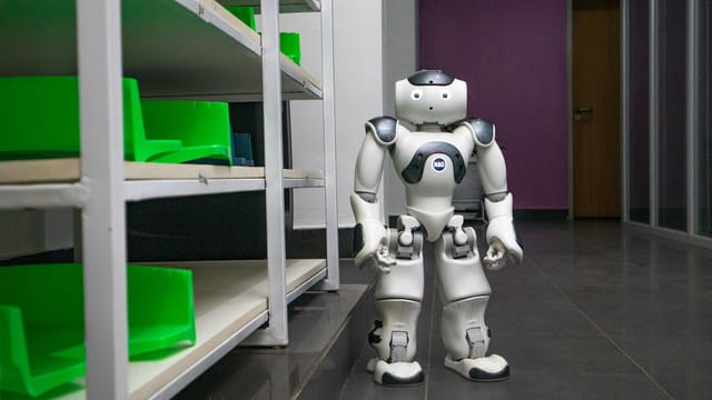 A humanoid robot standing in a modern corridor with shelves, representing futuristic technology.