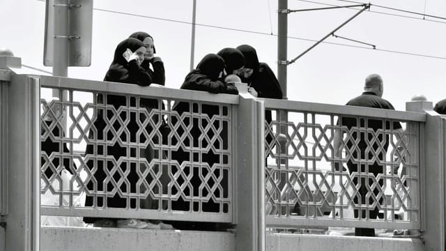 Group of women on an ornate bridge in monochrome, evoking cultural diversity.