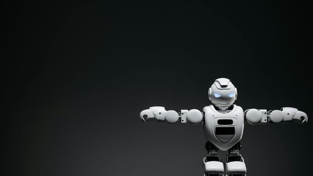 Studio shot of a humanoid robot with glowing eyes against a dark background, offering ample copyspace.