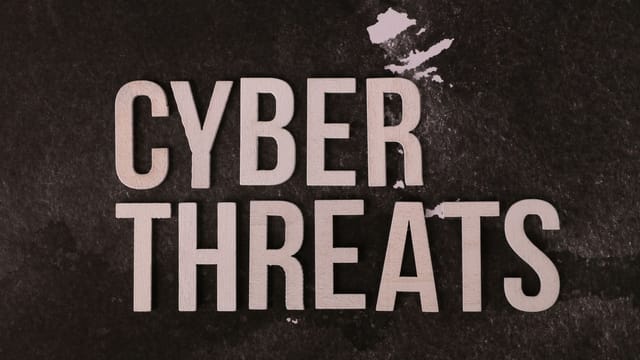 The phrase 'Cyber Threats' displayed on a textured dark background, emphasizing digital security.