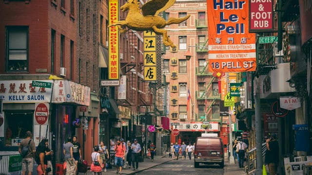 Vibrant Chinatown street in New York City filled with people and colorful signs.