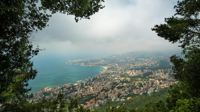 Breathtaking aerial view of Harissa, Lebanon's coastline, framed by lush greenery on a hazy day.