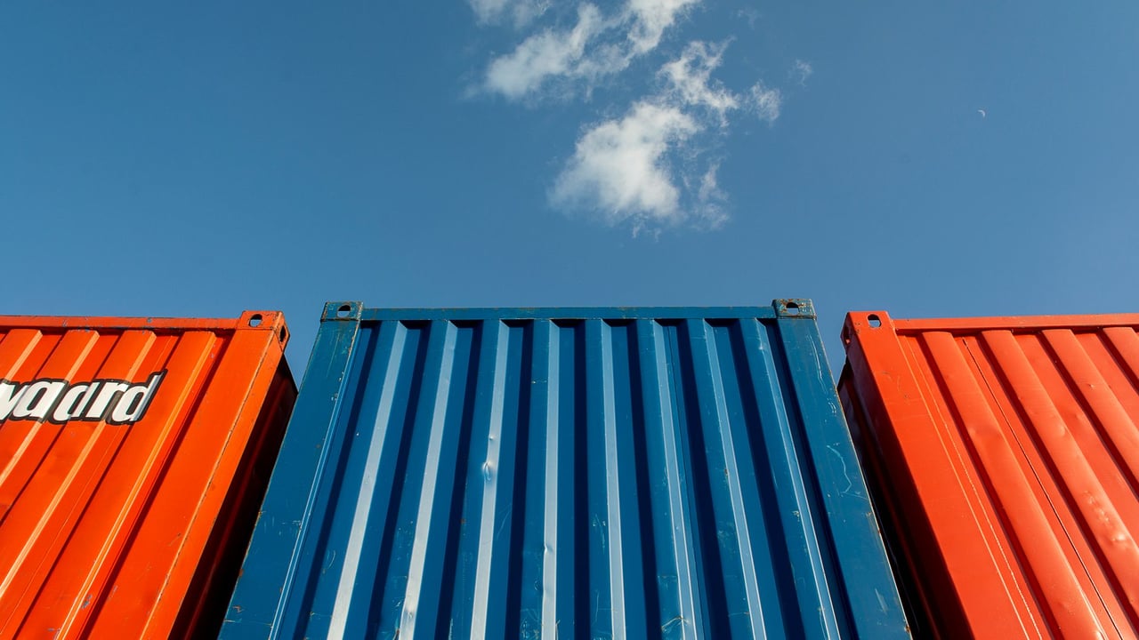 Illustrative image: Vibrant red and blue shipping containers under a clear sky, perfect for industrial themes.