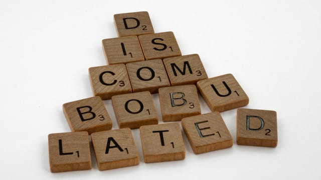 Scrabble tiles arranged to spell 'discombobulated' on a clean white surface, ideal for concept art.