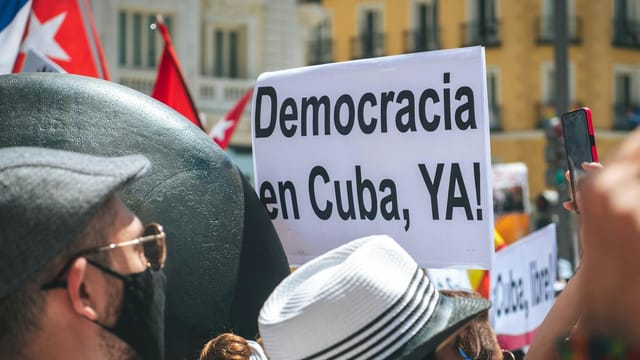 A vibrant street protest advocating for democracy in Cuba with visible signs.