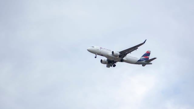 LATAM Airlines commercial airplane soaring through overcast skies near Londrina, Brazil.