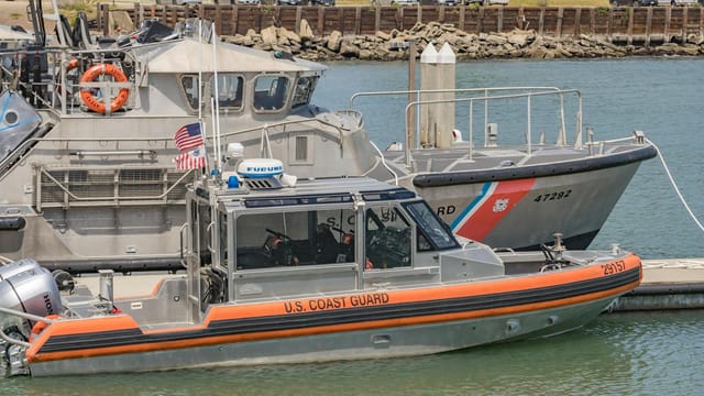 Two U.S. Coast Guard boats docked at a harbor, ready for action.
