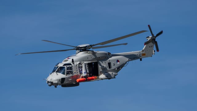 A military helicopter flying in a clear blue sky, showcasing aviation technology.