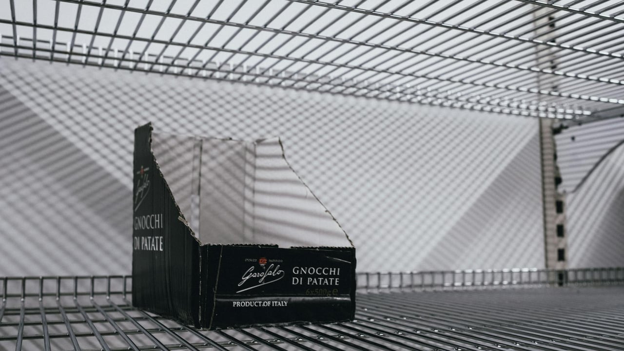 An empty supermarket shelf with an Italian gnocchi box symbolizing scarcity.