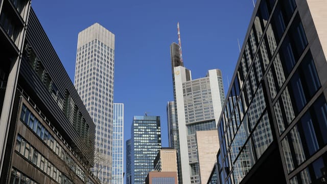 Skyline of skyscrapers in Frankfurt's bustling financial district under a clear blue sky.