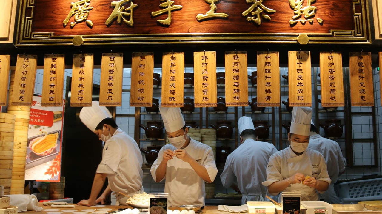 Talented chefs in action at a Chinese restaurant, preparing authentic dishes in an open kitchen.