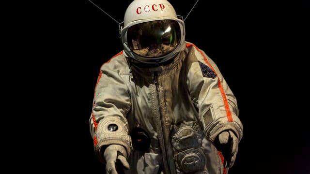 A detailed view of a vintage Soviet cosmonaut spacesuit displayed against a black background.