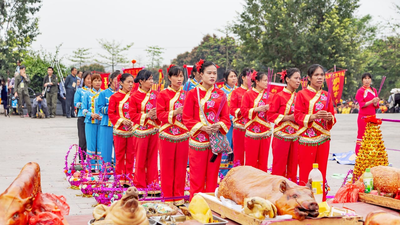 A vibrant traditional ceremony with people in cultural attire and offerings in Guangxi, China.