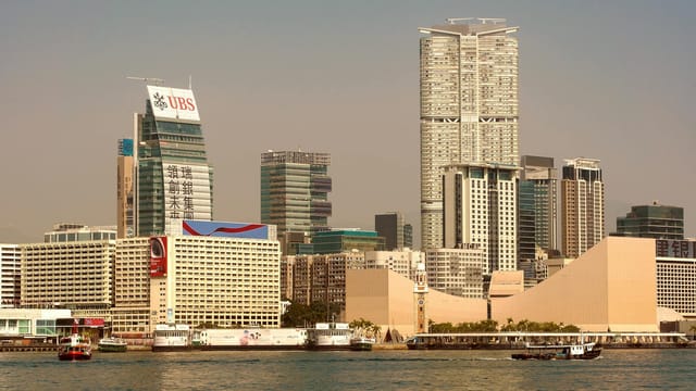 Explore the dynamic skyline of Hong Kong with towering skyscrapers and bustling waterfront activity.