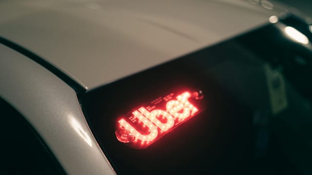 Close-up of a ride-sharing car with a bright red illuminated sign for night-time travel.
