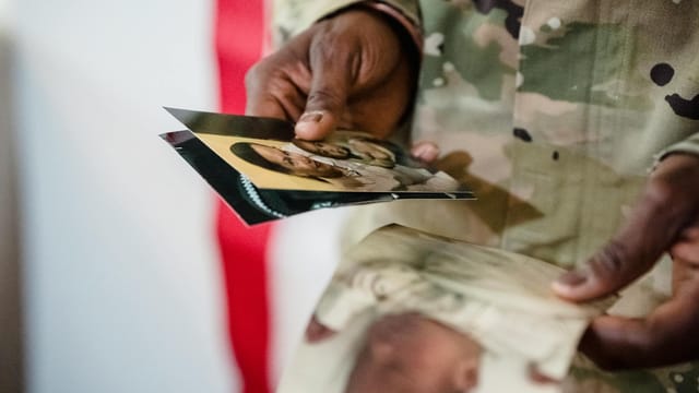 A soldier in uniform holding cherished family photos, embodying hope and memories.