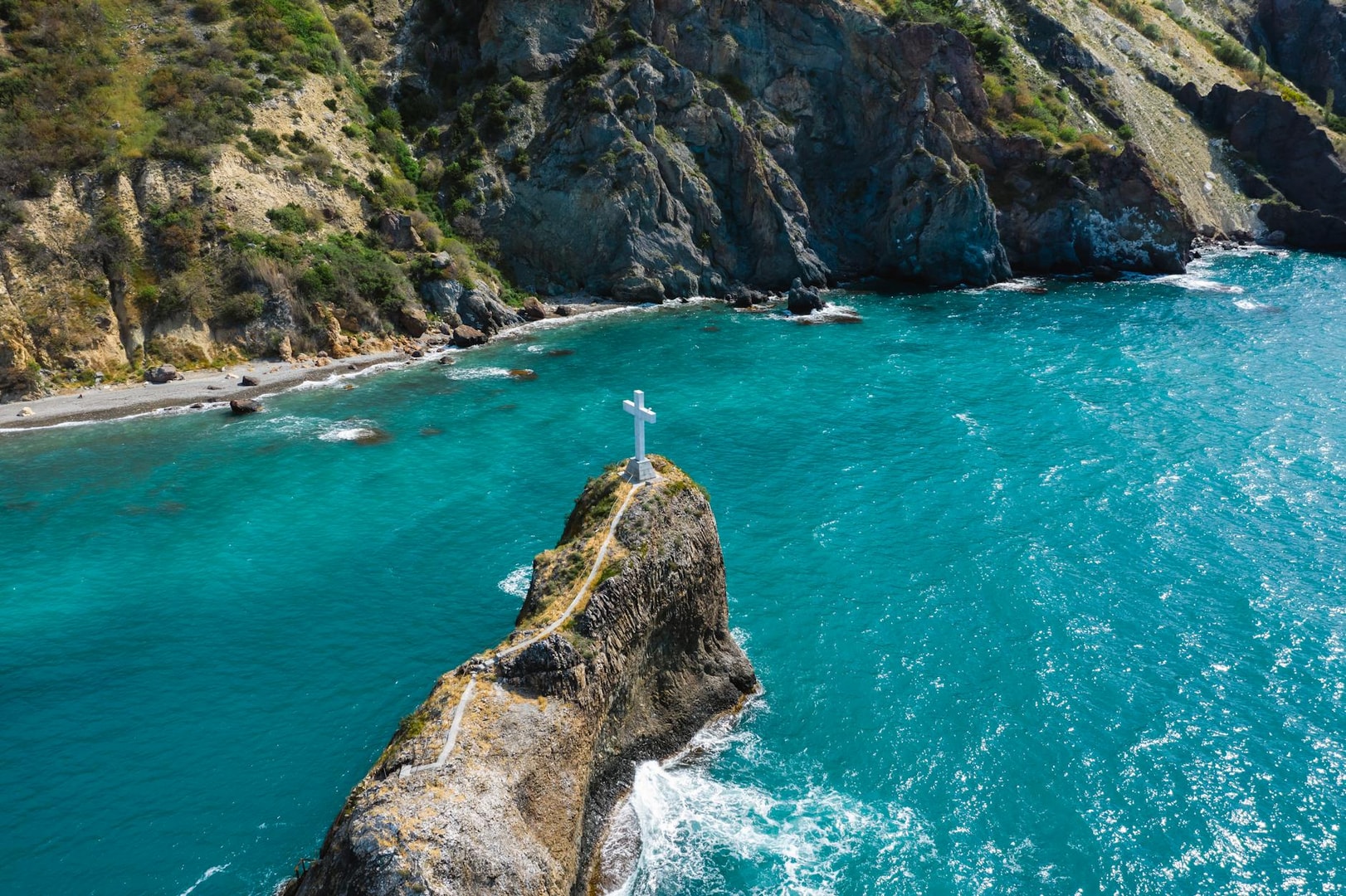 A stunning aerial shot of Cape Fiolent in Sevastopol featuring a coastal cross and turquoise waters.